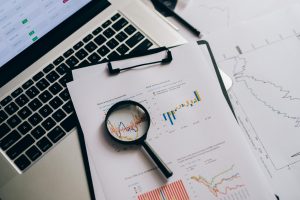 Overhead view of financial charts, laptop, and magnifying glass, ideal for business analysis themes.